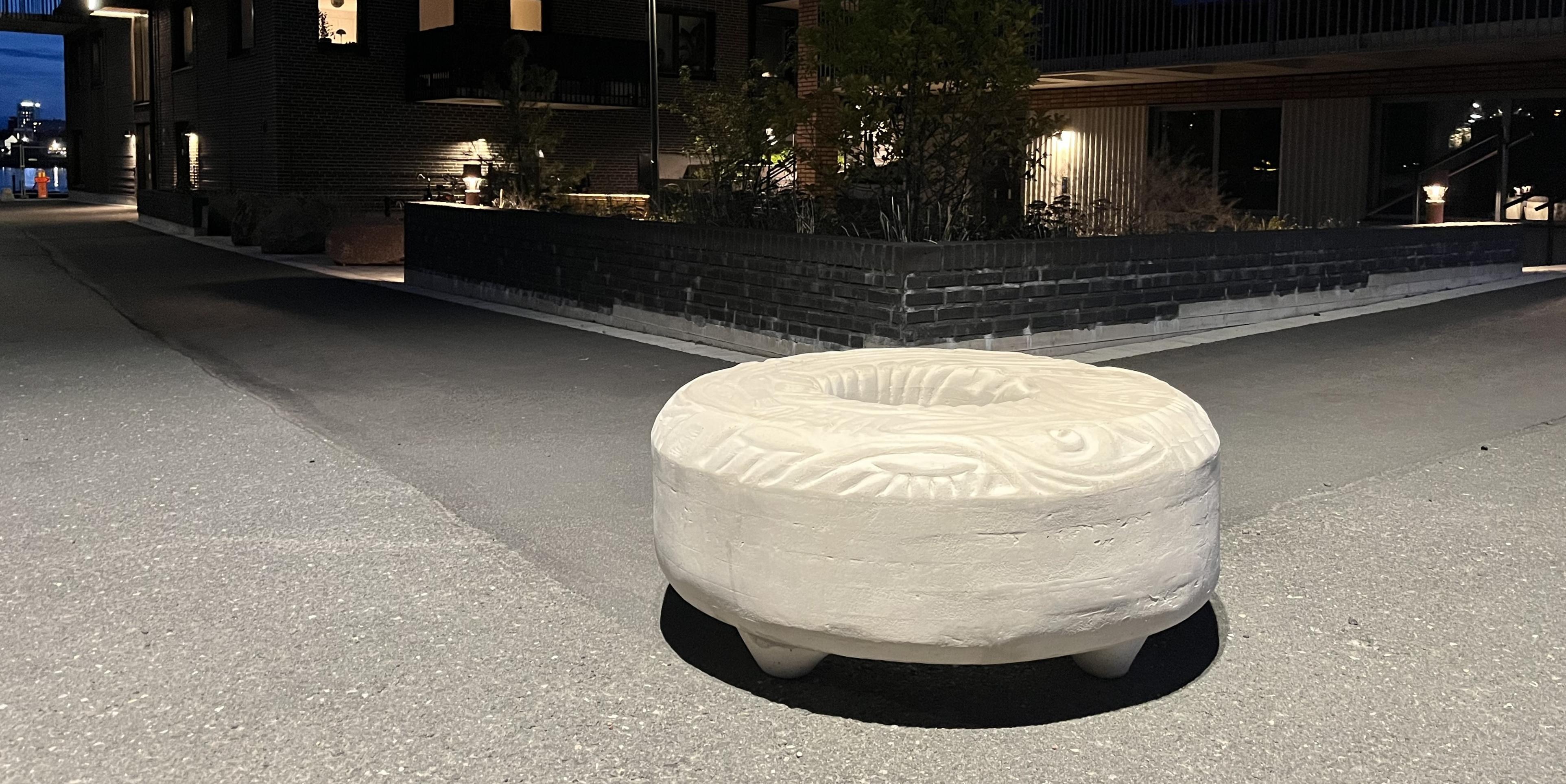Konstverket "Munken" står upplyst ute på en lokalgata. 