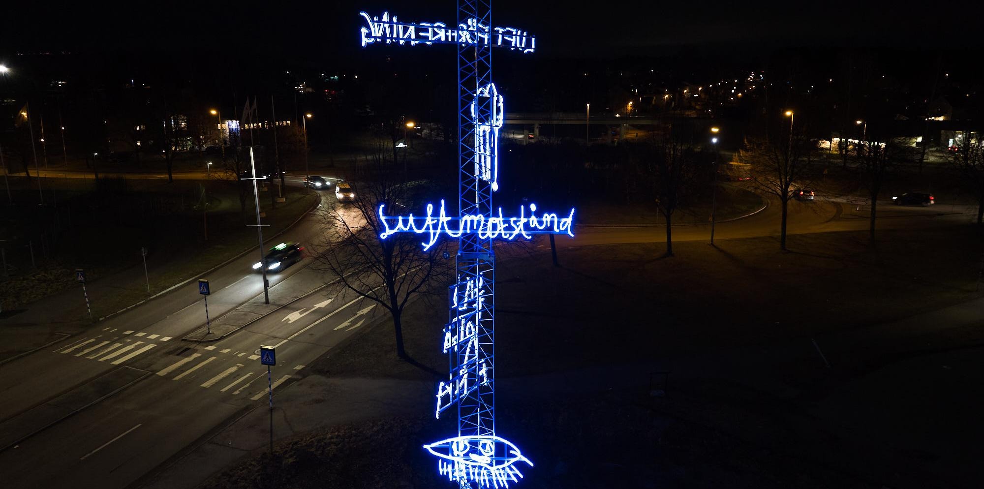 Ljuskonstverket fotat med en drönare. De blå färgerna på ljuset lyser i kontrast med den mörka kvällshimlen.
