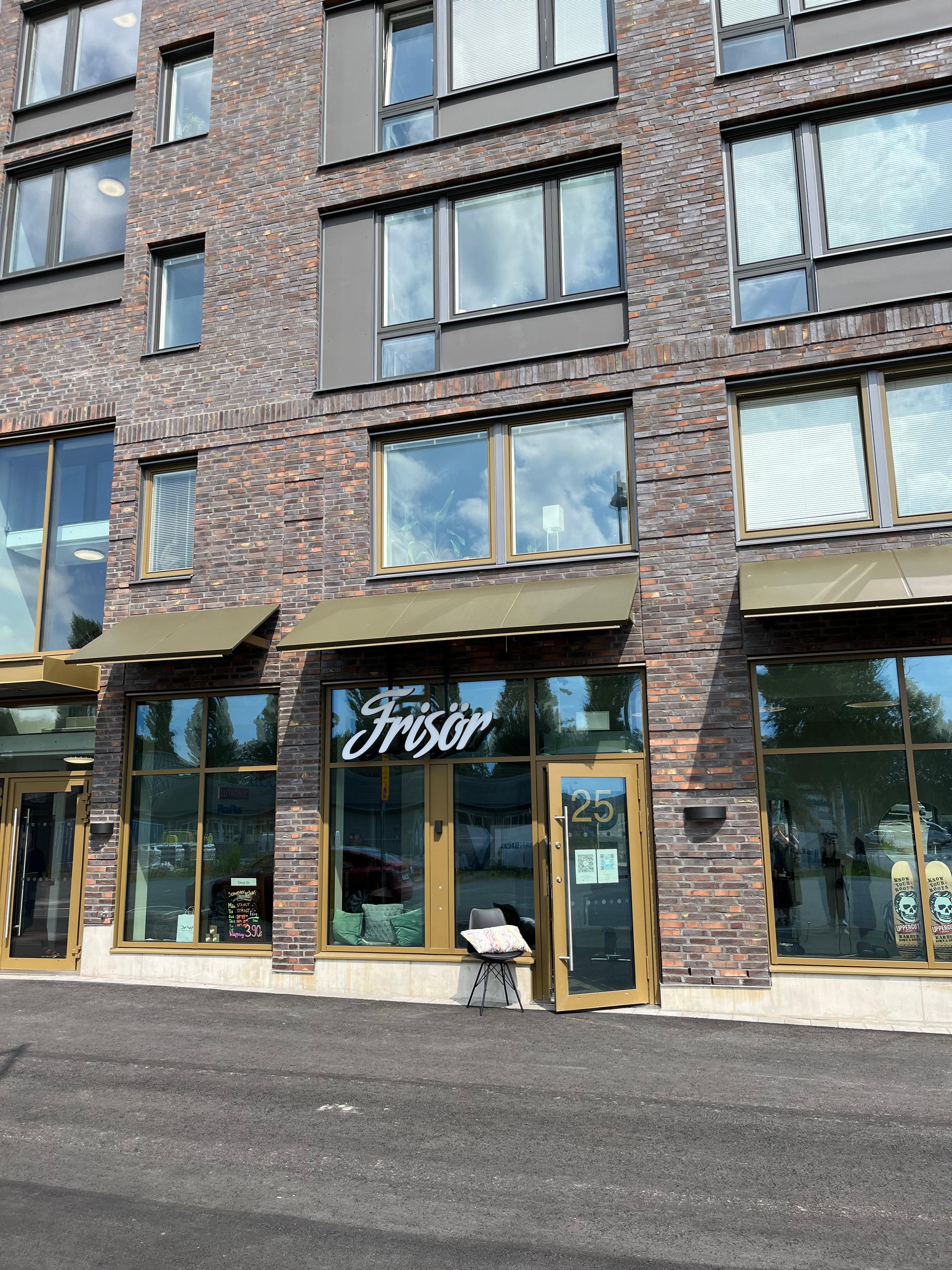 Glasfasad på ett tegelhus med skylten "frisör"
