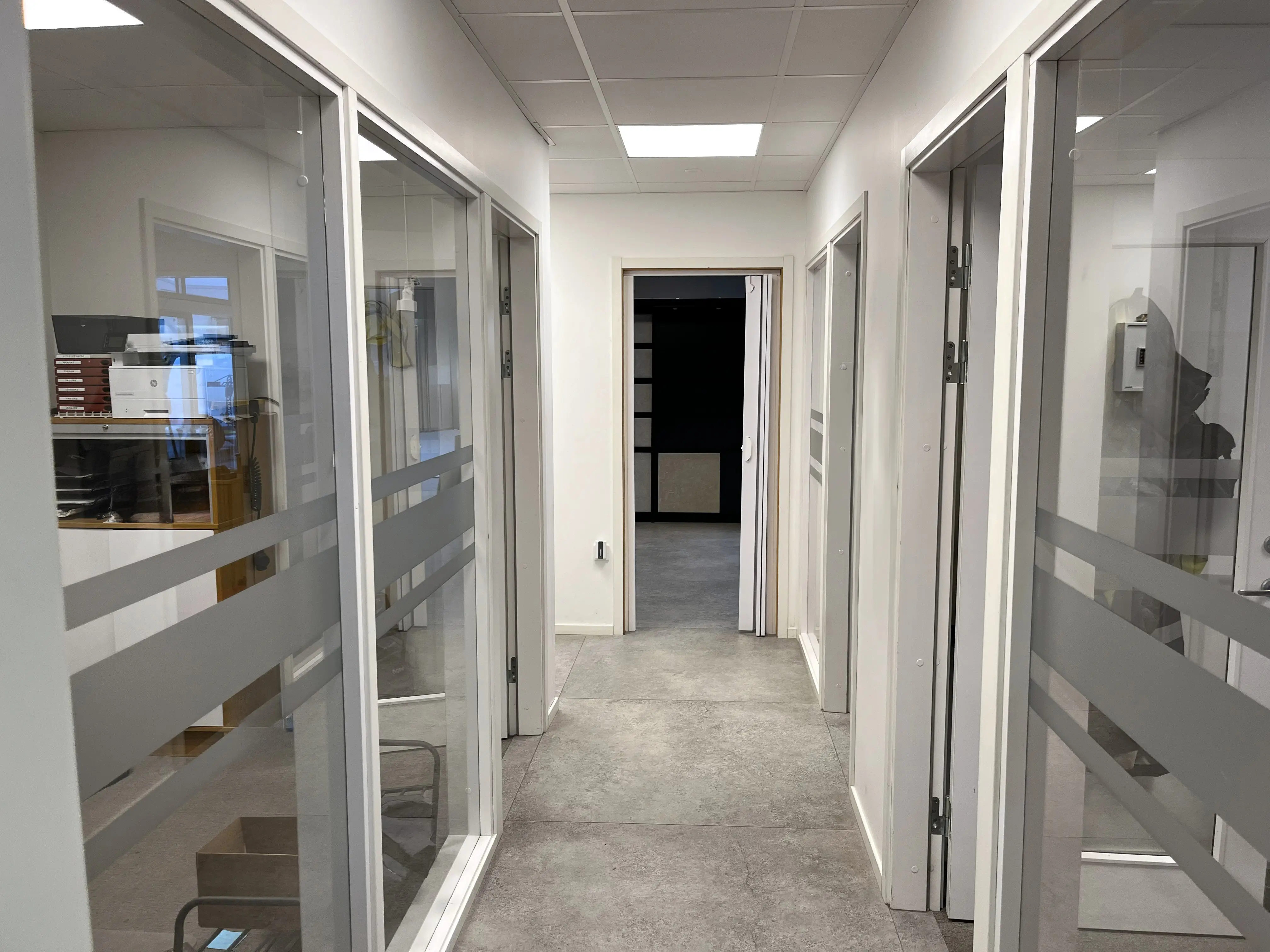 Korridor med kontor på båda sidor. Kontoren ramas in av glasväggar.