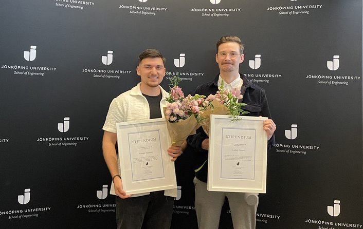 Stipendiaterna syns på med diplom och blommor mot en vägg med Jönköping Universitys logotype.