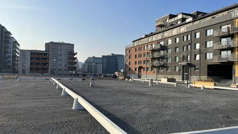 En stor plan grusyta framför tegelhus i olika färger.